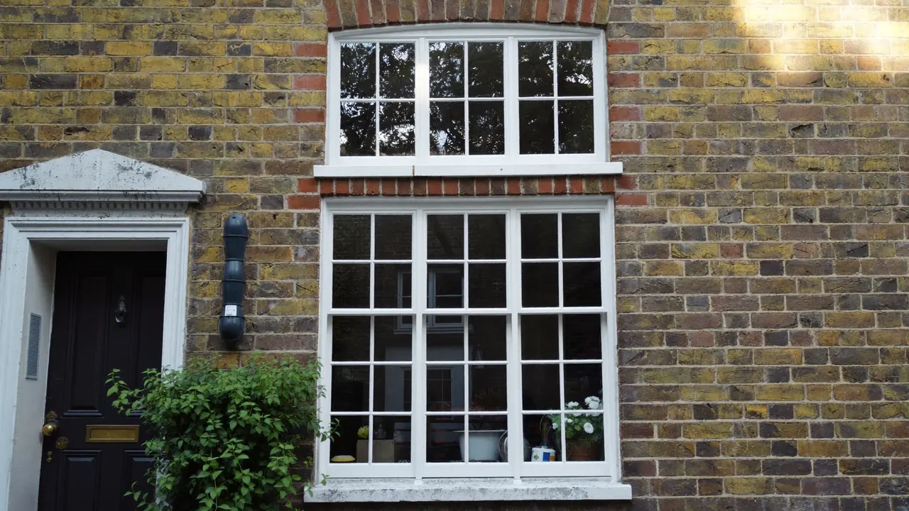 White Georgian bar windows with small panes on a period brick cottage